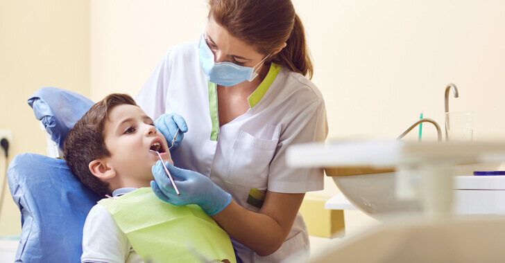 A dental hygienist examining a patient's teeth in a dental clinic.