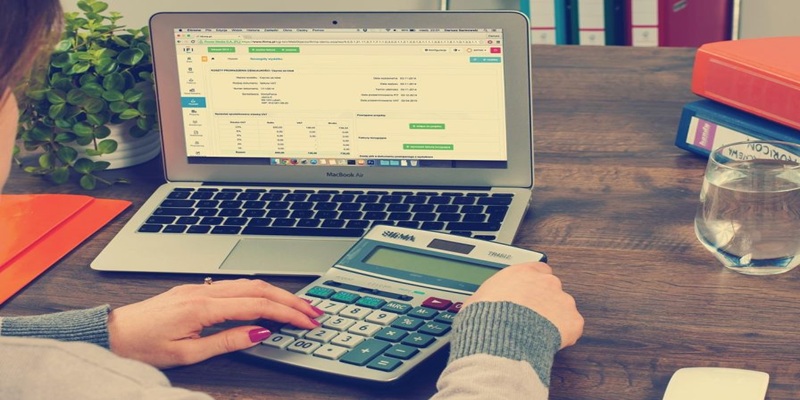 Person using calculator and laptop to evaluate intangible assets for tax filing in Canada