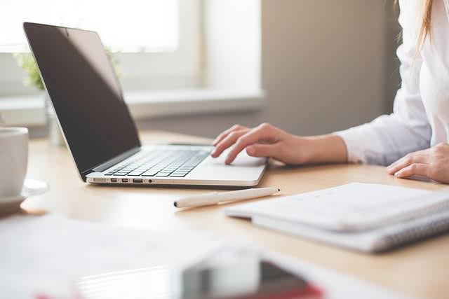 Woman working on tax planning strategy using a laptop and notebook in a bright office in Saskatoon