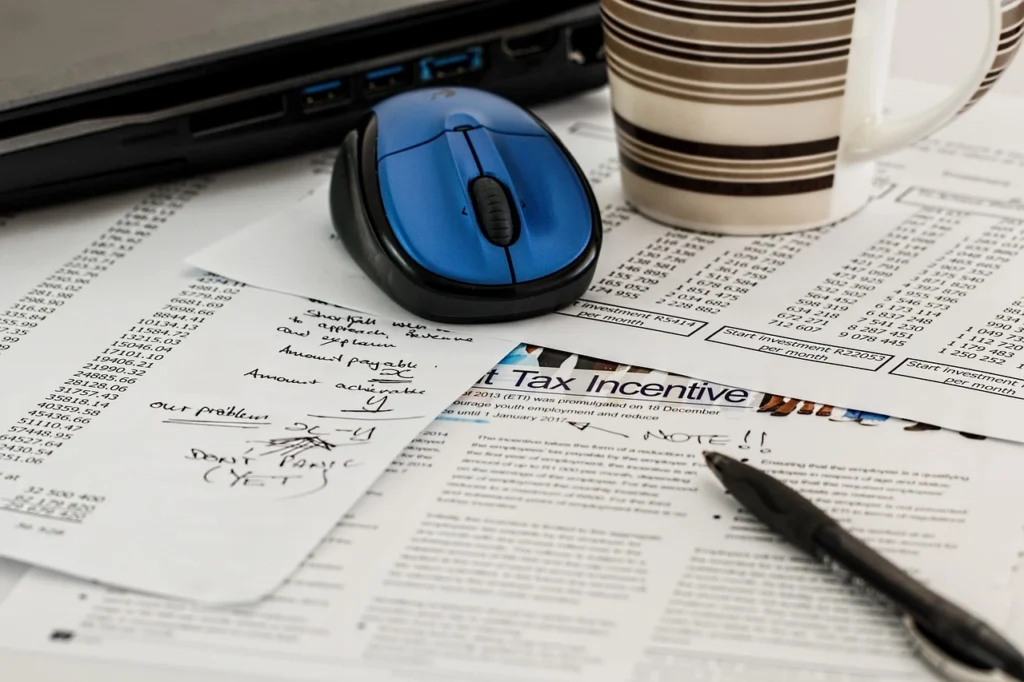 Papers, notes, and a computer mouse on a desk representing capital gains and tax-loss planning before year-end