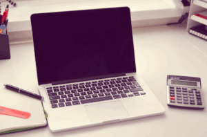 Laptop, calculator, and business planning materials on a desk, representing assurance services, financial reporting, and business advisory support in Canada.