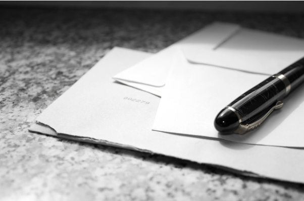 Business correspondence and documents with a pen on a desk, representing an audit management letter and post-audit recommendations.