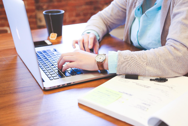 Business professional working on a laptop with financial documents, representing assurance services, financial reviews, and business reporting in Canada.
